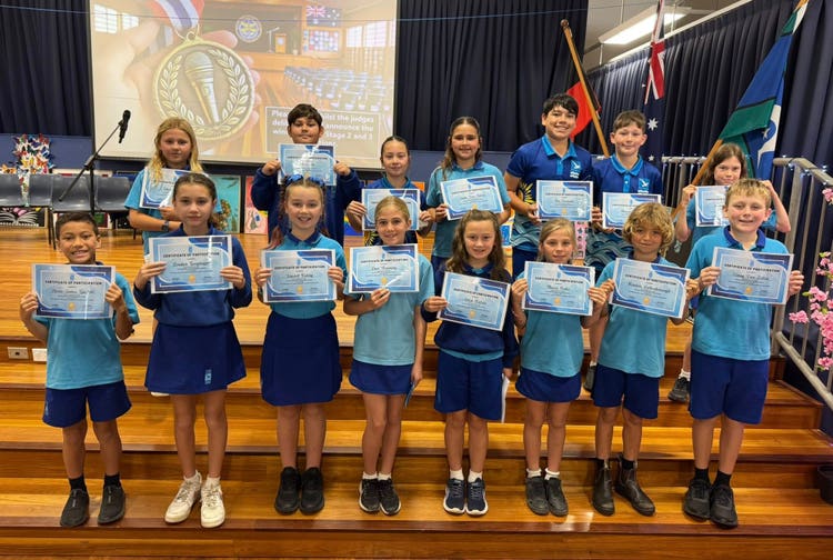 Students standing on the steps in the hall with their certificates for participating in the Stage Finals of the Public Speaking Competition