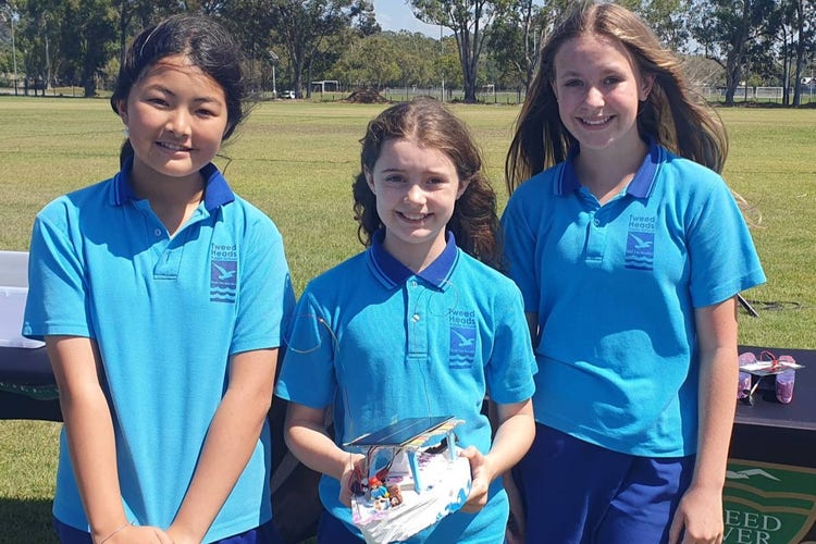 Three students posing with their solar boat that they designed, created and raced.