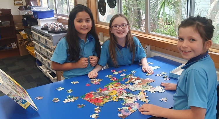 Three female students completing a jigsaw puzzle together